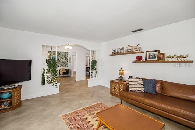 living room featuring visible vents, arched walkways, and baseboards