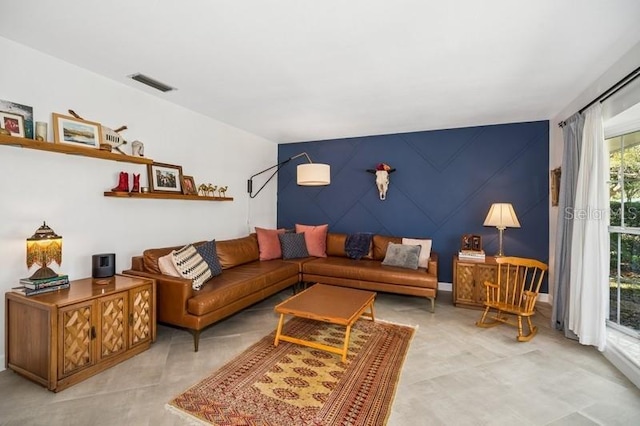 living area featuring visible vents and an accent wall