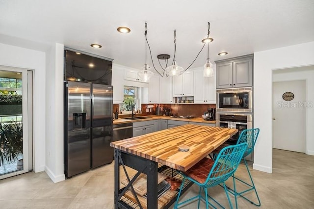 kitchen featuring backsplash, appliances with stainless steel finishes, gray cabinets, and a sink