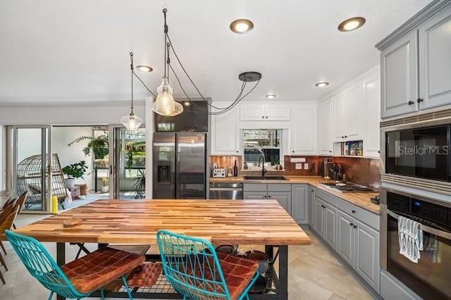 kitchen featuring gray cabinetry, a sink, appliances with stainless steel finishes, light countertops, and decorative backsplash