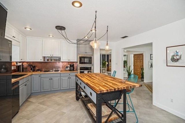 kitchen with visible vents, gray cabinetry, black appliances, light countertops, and backsplash