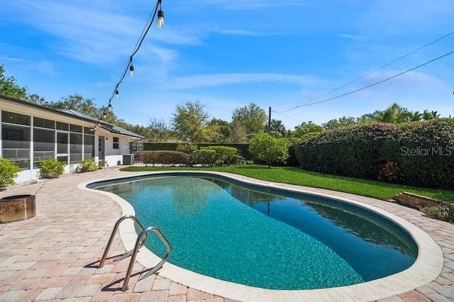 view of pool featuring a lawn, a fenced backyard, a sunroom, a fenced in pool, and a patio area