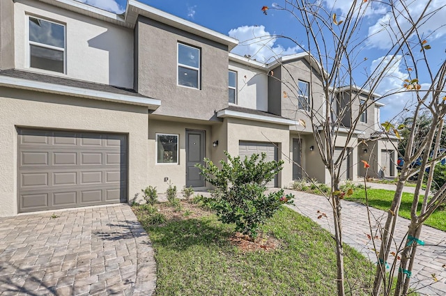 view of property featuring an attached garage, decorative driveway, and stucco siding