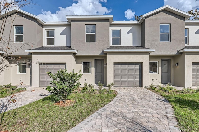 multi unit property with a garage, decorative driveway, and stucco siding