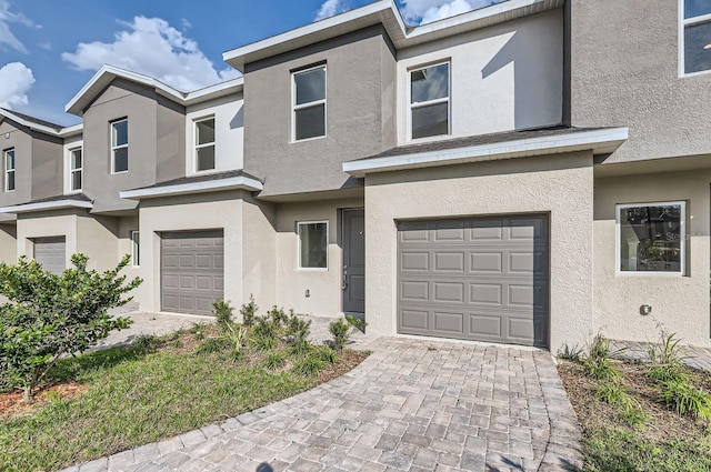 multi unit property featuring a garage, decorative driveway, and stucco siding