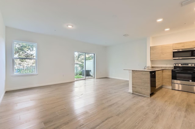 1209 S Station Pl Unit 306, Orlando, FL 32809 - kitchen featuring light brown cabinets, stainless steel appliances, a peninsula, open floor plan, and light countertops