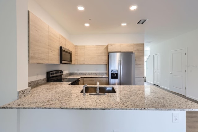 1209 S Station Pl Unit 306, Orlando, FL 32809 - kitchen featuring appliances with stainless steel finishes, light stone counters, a peninsula, light brown cabinetry, and a sink