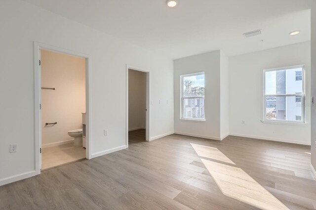 1209 S Station Pl Unit 306, Orlando, FL 32809 - unfurnished bedroom featuring light wood finished floors, ensuite bath, a walk in closet, and baseboards