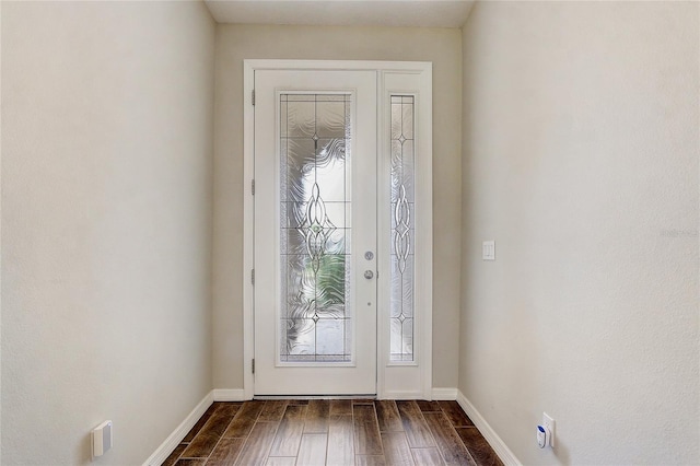 foyer entrance with dark wood-style flooring and baseboards