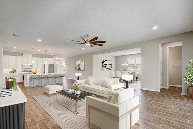 living area featuring wood finish floors, a textured ceiling, baseboards, and recessed lighting