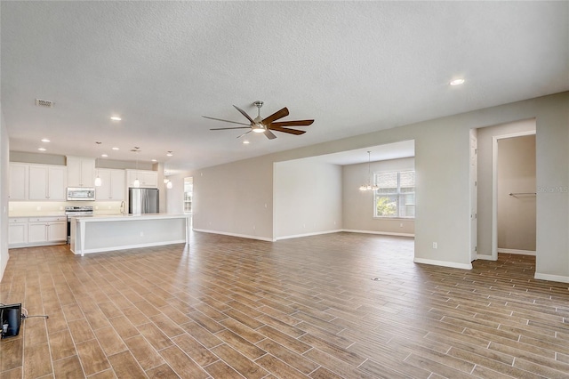 unfurnished living room with baseboards, ceiling fan with notable chandelier, a textured ceiling, light wood-style floors, and recessed lighting