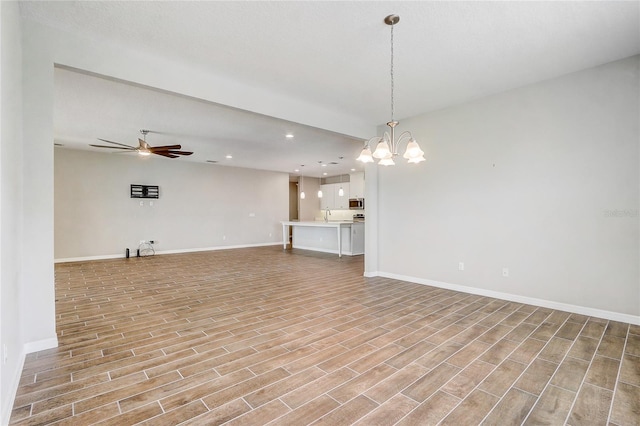 unfurnished living room with recessed lighting, light wood-style flooring, a sink, baseboards, and ceiling fan with notable chandelier