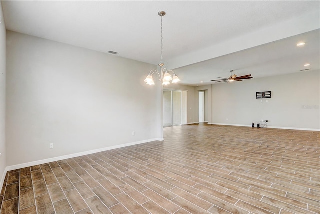 empty room with recessed lighting, visible vents, light wood-type flooring, baseboards, and ceiling fan with notable chandelier