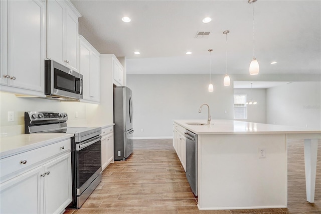 kitchen featuring light countertops, appliances with stainless steel finishes, hanging light fixtures, and a sink