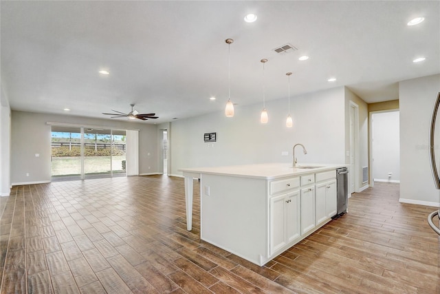 kitchen with visible vents, open floor plan, hanging light fixtures, light countertops, and a sink