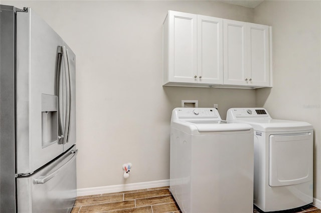 laundry room featuring wood tiled floor, cabinet space, independent washer and dryer, and baseboards