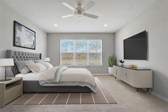 bedroom featuring light carpet, ceiling fan, a textured ceiling, and baseboards