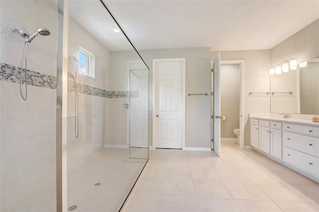 full bathroom featuring baseboards, tiled shower, toilet, tile patterned flooring, and vanity