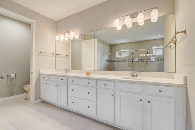 bathroom featuring double vanity, baseboards, toilet, walk in shower, and a sink