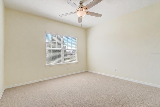 spare room with light carpet, ceiling fan, and baseboards