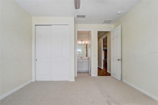 unfurnished bedroom featuring baseboards, visible vents, a closet, and light colored carpet