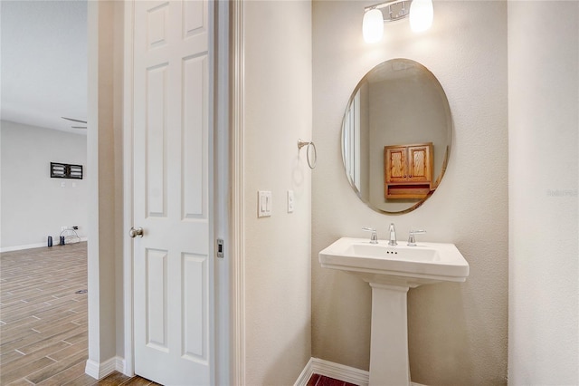 bathroom with a sink, baseboards, and wood finished floors