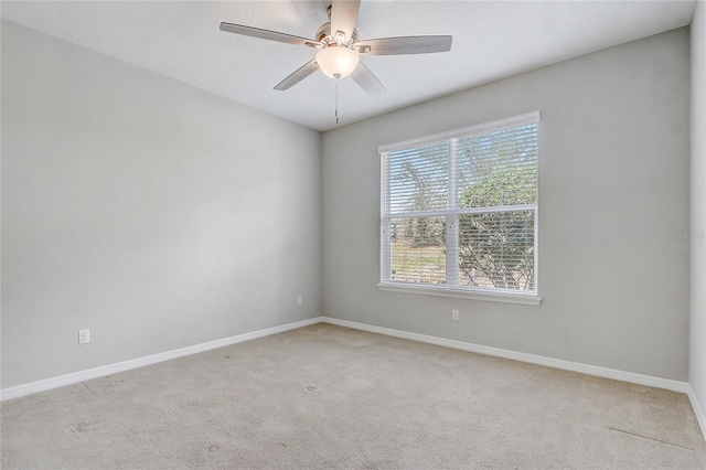 empty room with baseboards, a ceiling fan, and light colored carpet