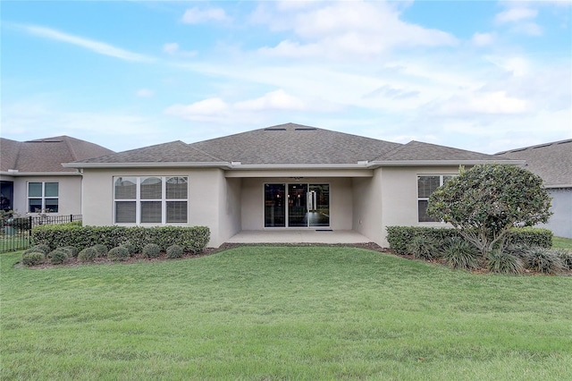 rear view of house featuring a yard, fence, a patio, and stucco siding