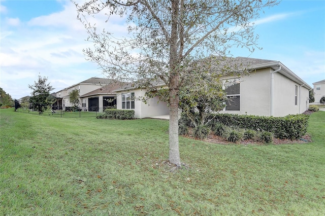 exterior space featuring a lawn, fence, and stucco siding