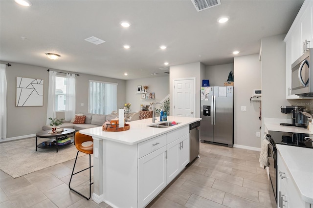 kitchen featuring a center island with sink, sink, stainless steel appliances, and white cabinetry