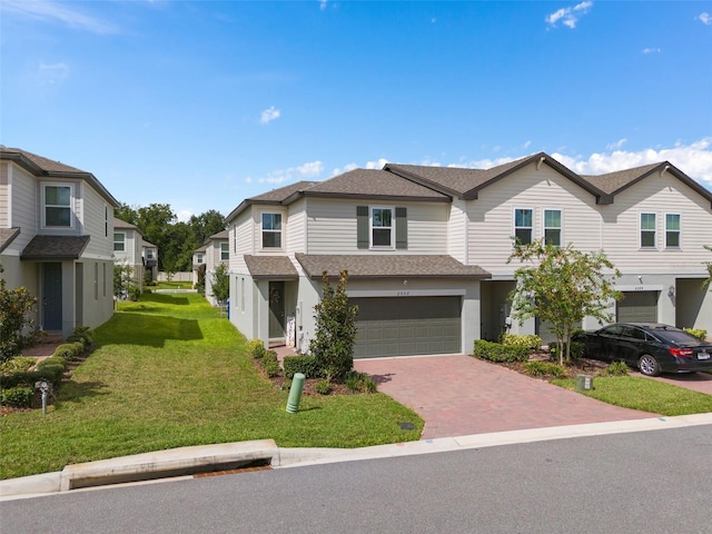 2052 Milkweed St, Ocoee, FL 34761 - townhome / multi-family property featuring roof with shingles, an attached garage, decorative driveway, and a front lawn