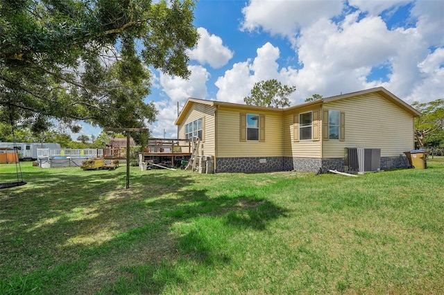 view of property exterior featuring a deck, a yard, cooling unit, and a pool