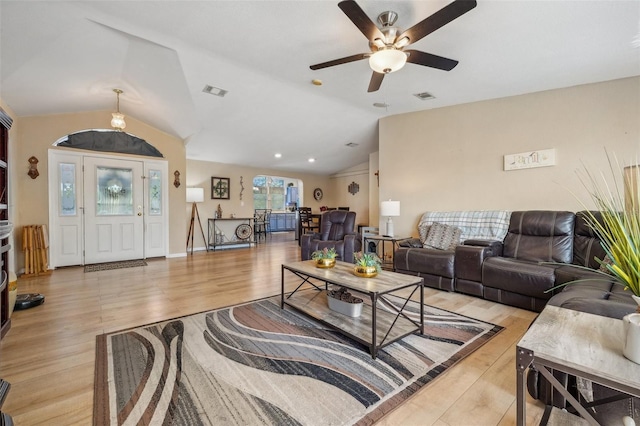 living area with lofted ceiling, light wood finished floors, and visible vents