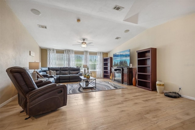 living area with light wood-style floors, baseboards, visible vents, and vaulted ceiling