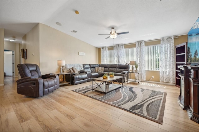 living area with light wood finished floors, visible vents, ceiling fan, vaulted ceiling, and a textured ceiling