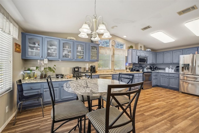 kitchen with visible vents, glass insert cabinets, blue cabinets, stainless steel appliances, and pendant lighting