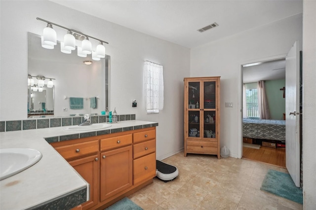 ensuite bathroom with ensuite bathroom, visible vents, vanity, and baseboards