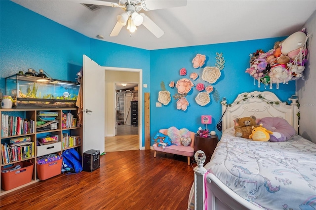 bedroom featuring a ceiling fan, visible vents, and wood finished floors