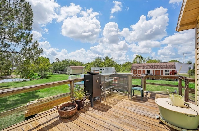 deck with a storage unit, a lawn, and an outdoor structure