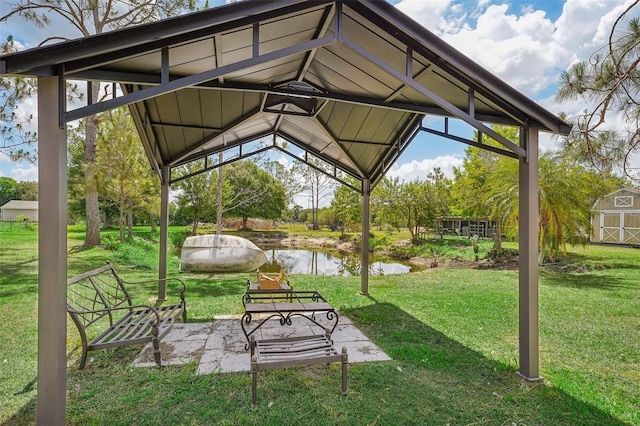 view of property's community with an outbuilding, a water view, a gazebo, a lawn, and a storage unit