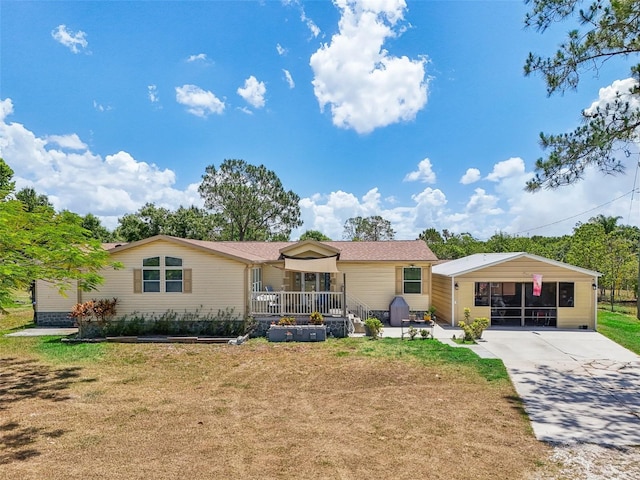 view of front of home with a carport, covered porch, a front lawn, and concrete driveway