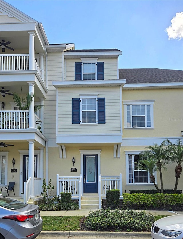 view of property with a balcony, a porch, a ceiling fan, and stucco siding