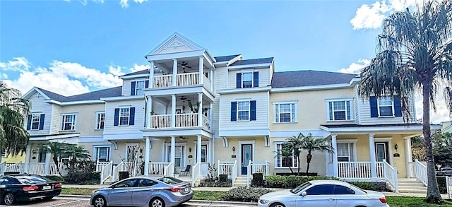 view of property featuring a balcony, a residential view, stucco siding, and ceiling fan