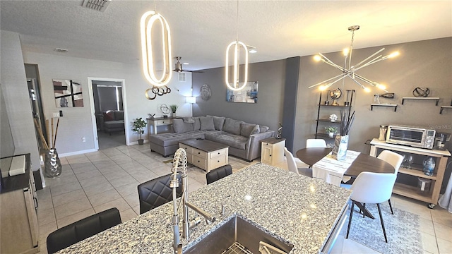 136 Mcleods Way, Winter Springs, FL 32708 - kitchen with light tile patterned floors, a chandelier, a textured ceiling, light stone counters, and baseboards
