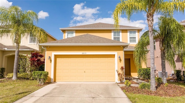 traditional-style home with roof with shingles, driveway, an attached garage, and stucco siding