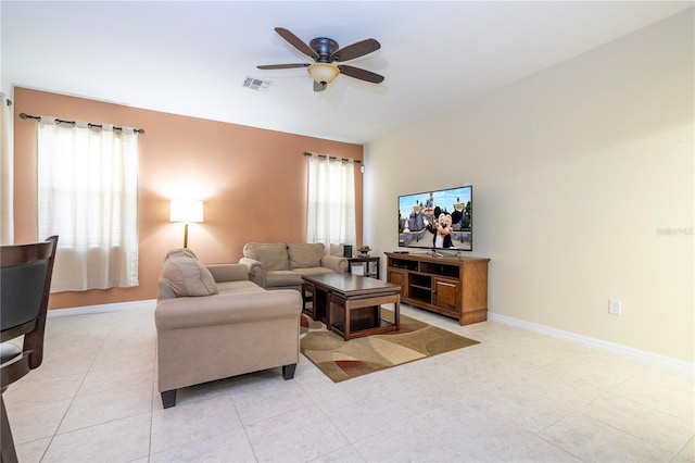 living room with visible vents, baseboards, ceiling fan, and a wealth of natural light