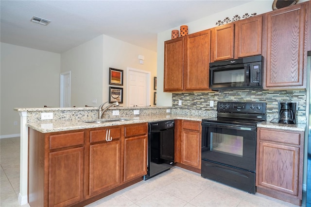 kitchen featuring brown cabinets, a peninsula, a sink, black appliances, and backsplash