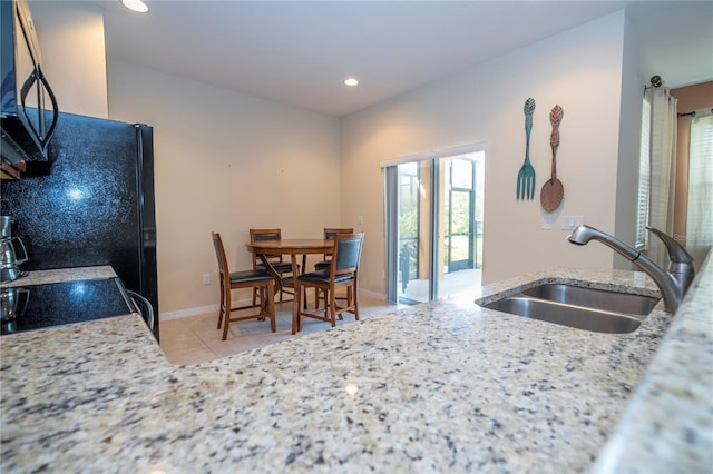 kitchen with light tile patterned floors, baseboards, range, a sink, and recessed lighting