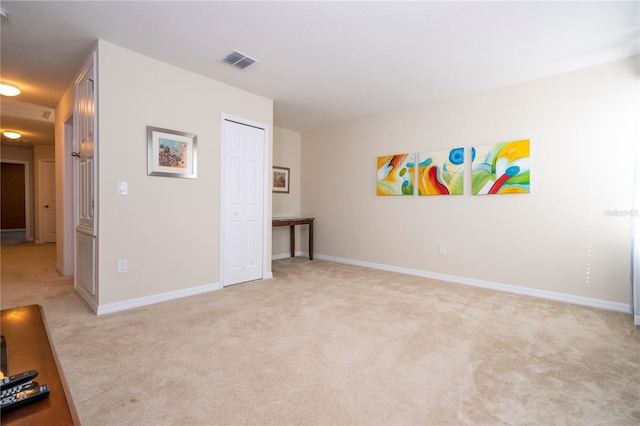 unfurnished room featuring baseboards, visible vents, and light colored carpet