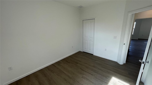 unfurnished bedroom with dark wood-type flooring and a closet